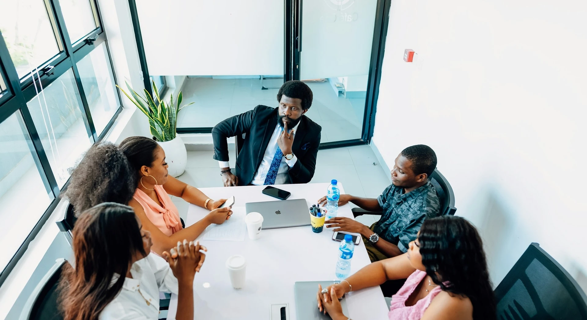 Équipe de professionnels africains réunie autour d'une table de travail dans un bureau vitré.